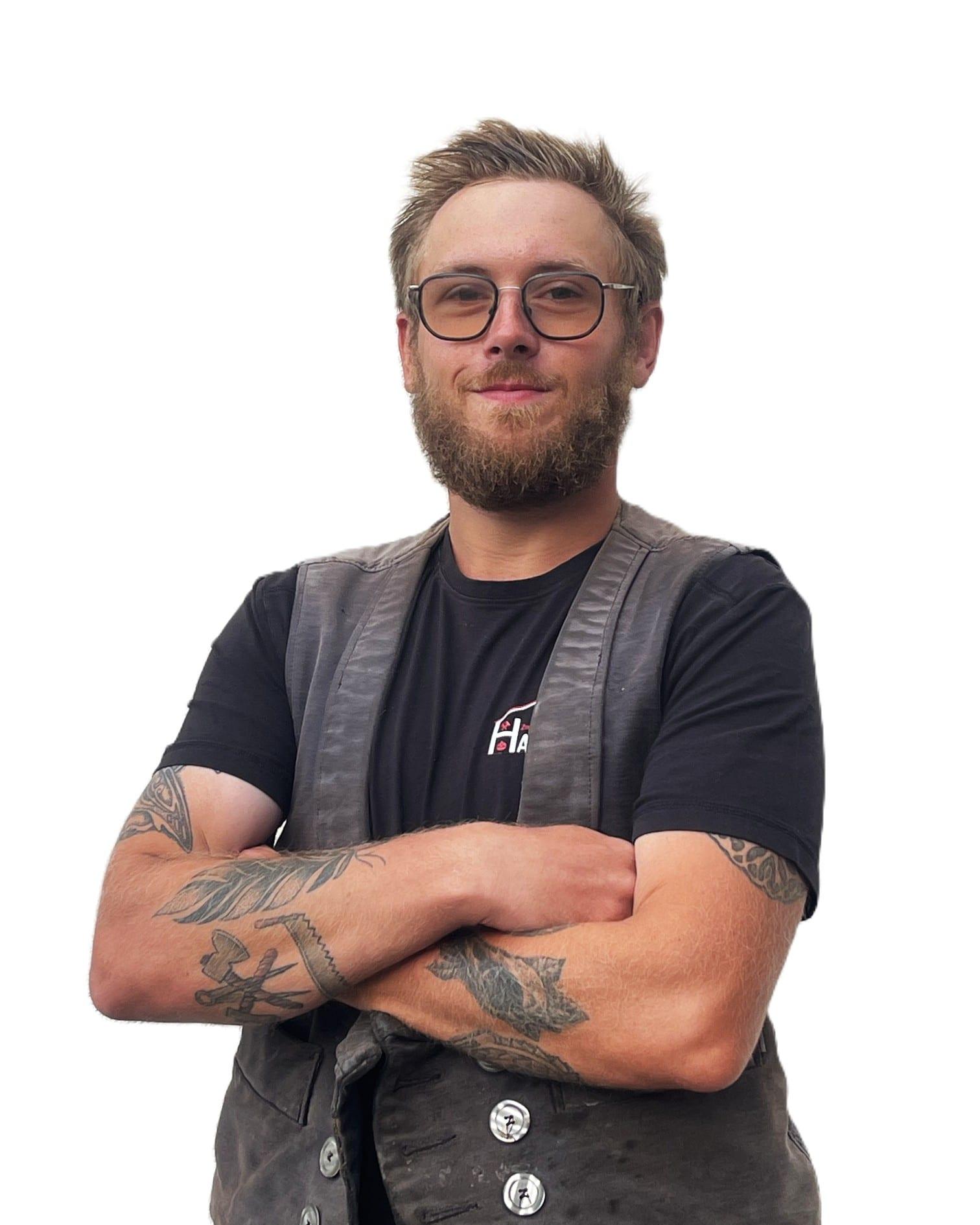 Porträt von Zimmerergeselle Florian Lange mit Bart und Brille, in traditioneller Zimmermannskluft.